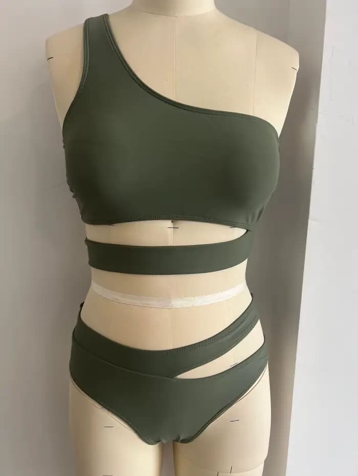 Bikini femme 2026, haut asymétrique vert olive, bas taille haute à découpes latérales, maillot de bain deux pièces uni avec haut court